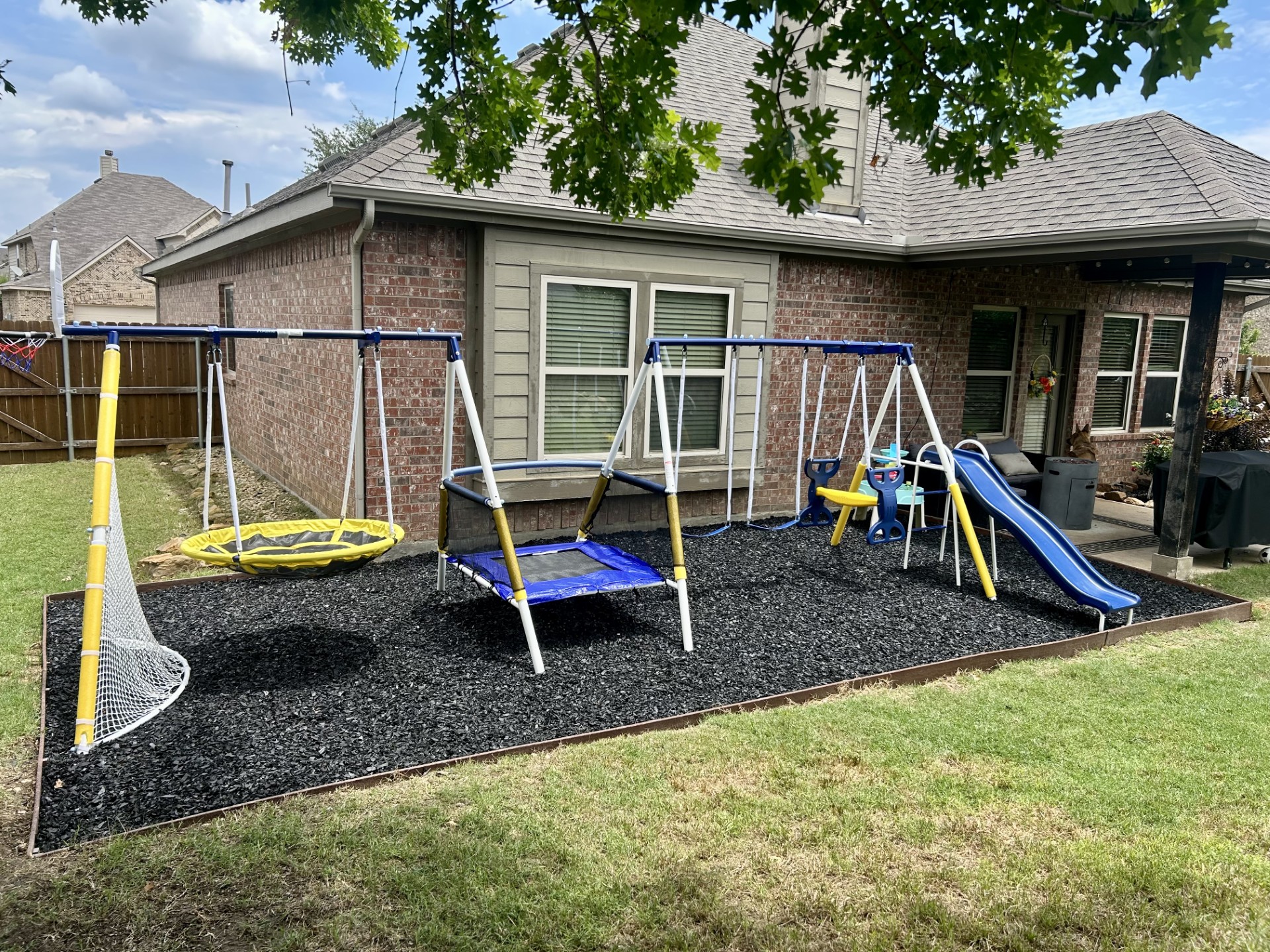 Backyard playground build with rubber mulch pit